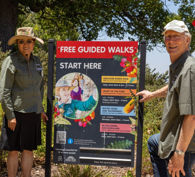 Guests smiling and pointing and guided walk sign