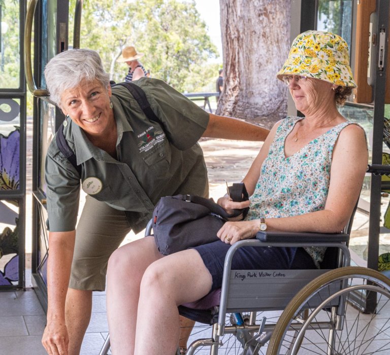 Sue smiling and helping a guest in a wheelchair